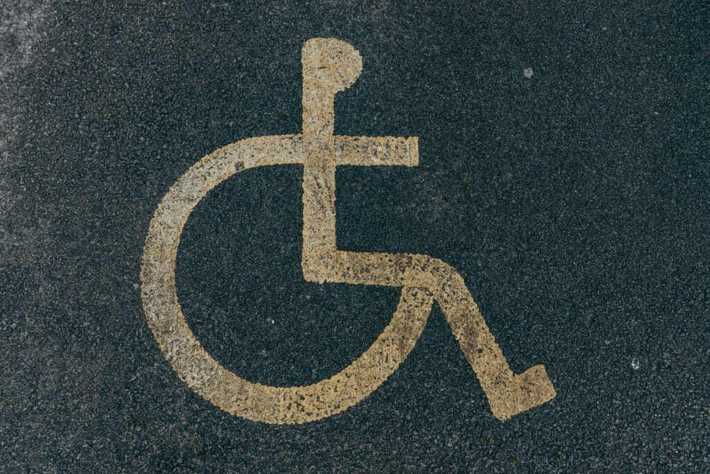 Accessibility Statement Close-up of a yellow accessibility symbol marked on a dark asphalt surface.