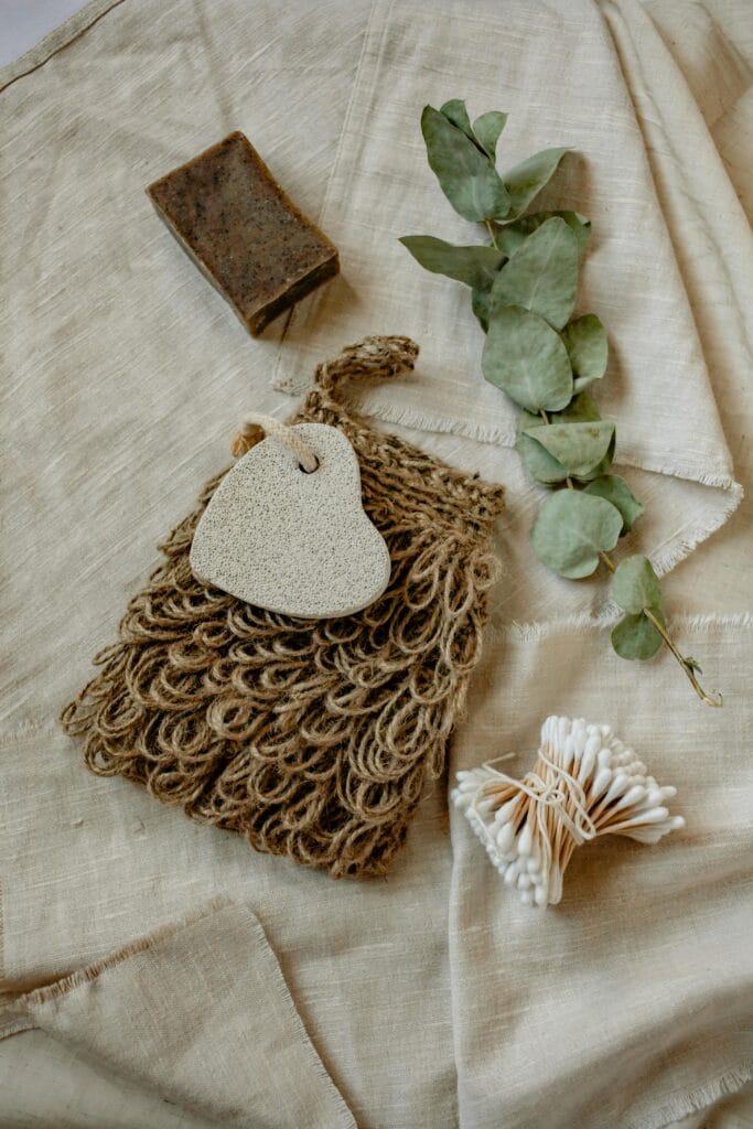 A flat lay of eco-friendly bath essentials including soap, eucalyptus leaves, and cotton buds.