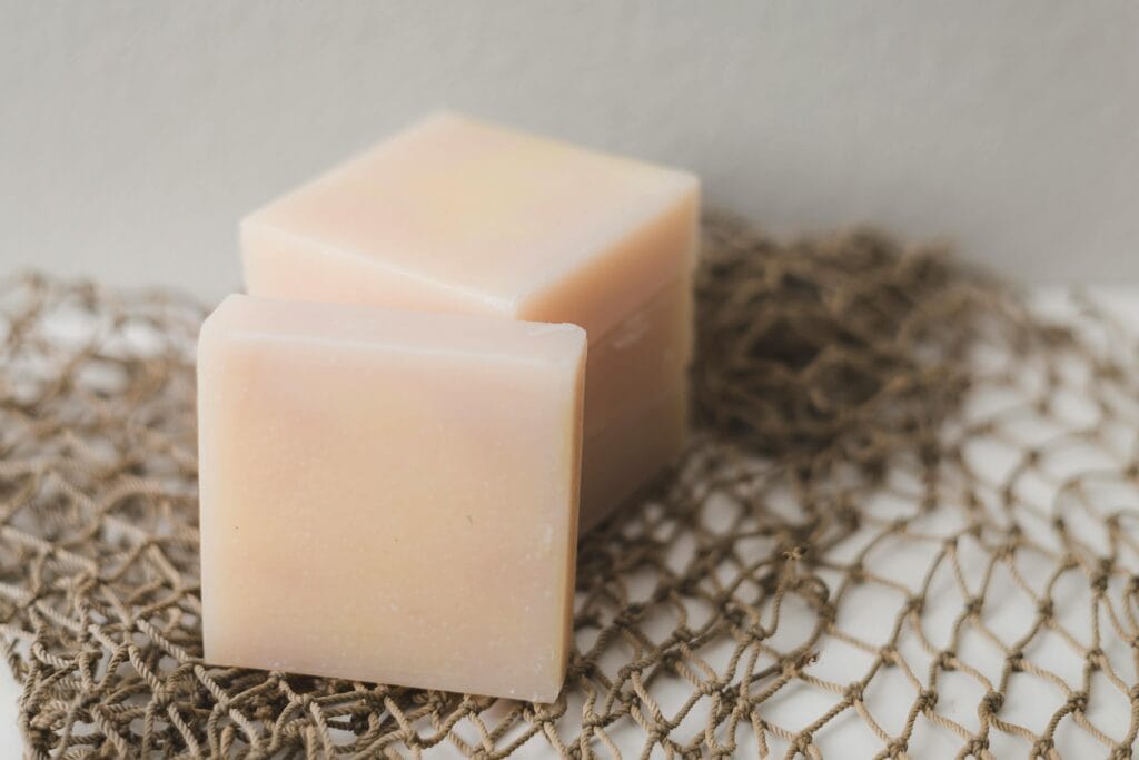 Two bars of natural handmade soap placed on a rustic netting backdrop, perfect for a spa theme.