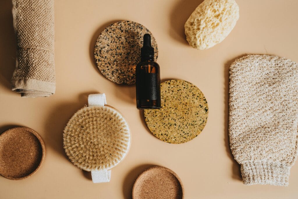 A collection of eco-friendly bathing tools including brushes and a bottle arranged on a beige surface.